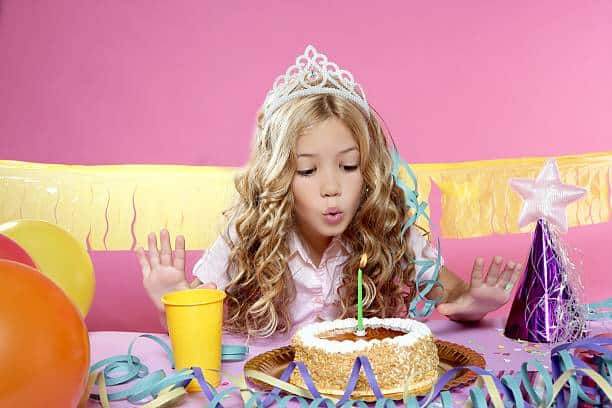 happy little blond girl blowing cake candle in birthday party picture id119391087