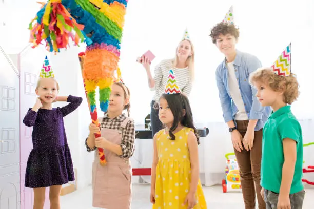 girl striking pinata at birthday party picture id1083907026